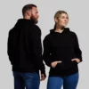 Unmatched unisex hoodie (black) Hettegenser. Mann og kvinne iført sorte hettegensere med lomme foran.