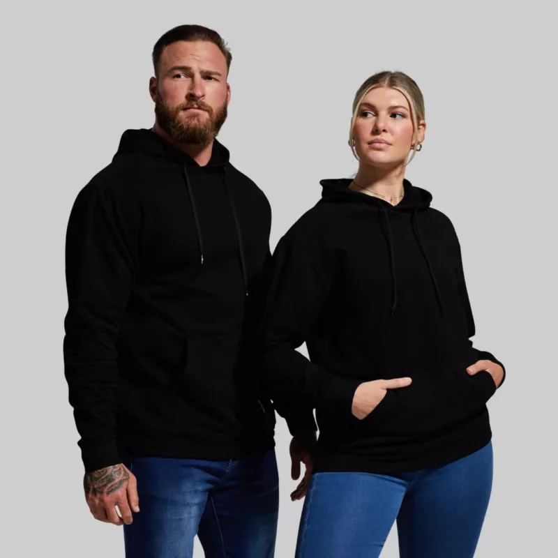 Mann og kvinne står vendt mot kamera iført sorte hettegensere med lomme foran.