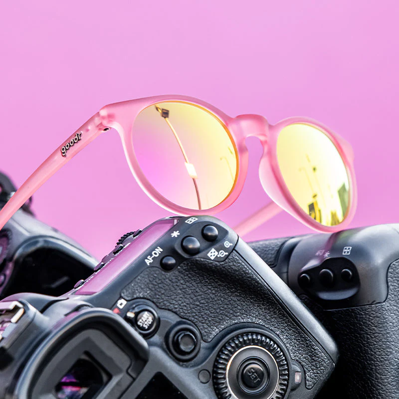 Retro solbriller Lys rosa med oransje glass, mot rosa bakgrunn